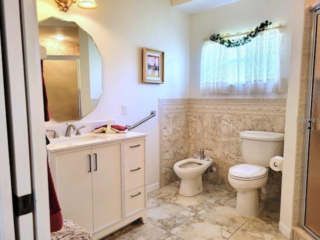 bathroom with a bidet, toilet, and vanity