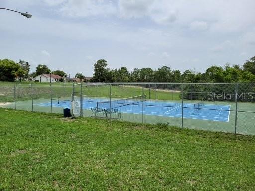 view of tennis court with a yard