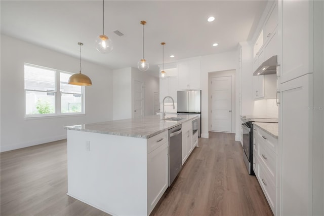 kitchen with an island with sink, white cabinetry, decorative light fixtures, range hood, and appliances with stainless steel finishes