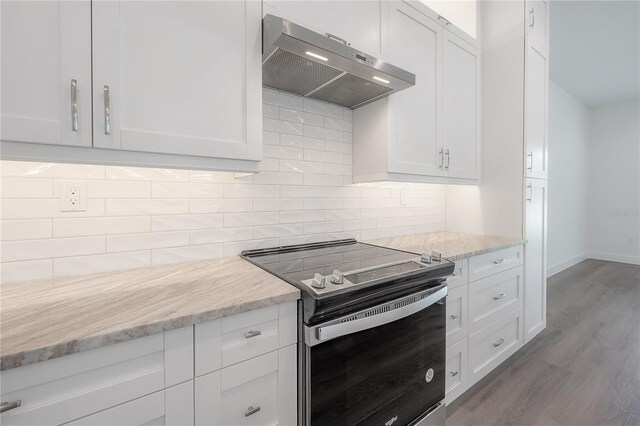 kitchen with white cabinetry, stainless steel range with electric cooktop, backsplash, light stone counters, and wood-type flooring