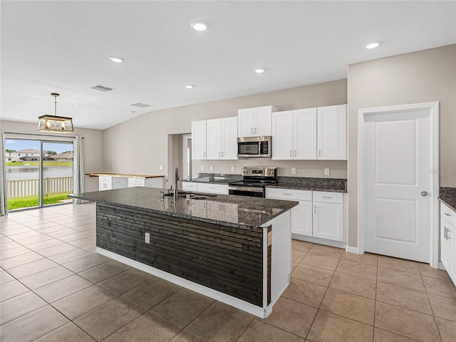 kitchen featuring sink, a kitchen island with sink, stainless steel appliances, a water view, and white cabinets