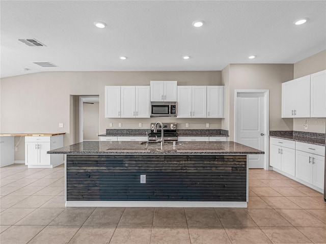 kitchen featuring stainless steel appliances, sink, a kitchen island with sink, and dark stone counters