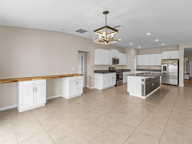 kitchen featuring hanging light fixtures, appliances with stainless steel finishes, a center island with sink, and white cabinets