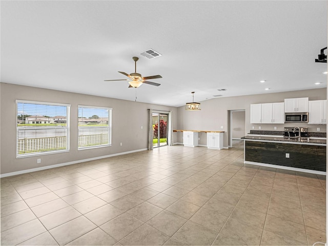 unfurnished living room featuring light tile patterned flooring, sink, and ceiling fan