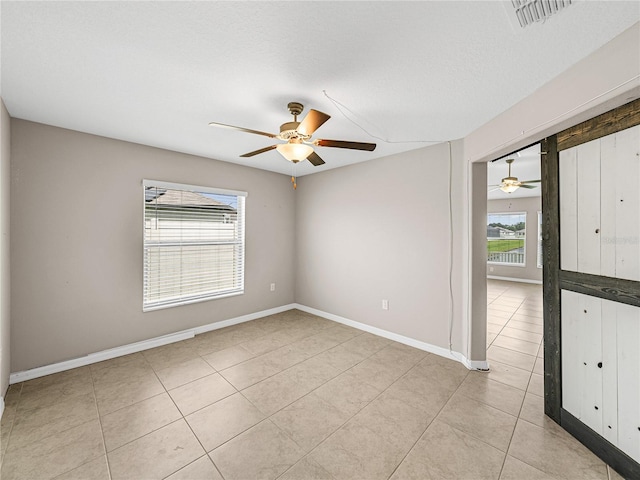 tiled empty room featuring a textured ceiling and ceiling fan