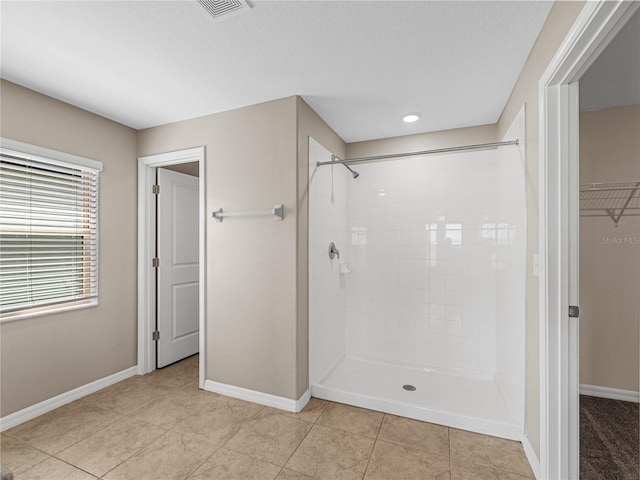 bathroom with a tile shower, tile patterned flooring, and a textured ceiling