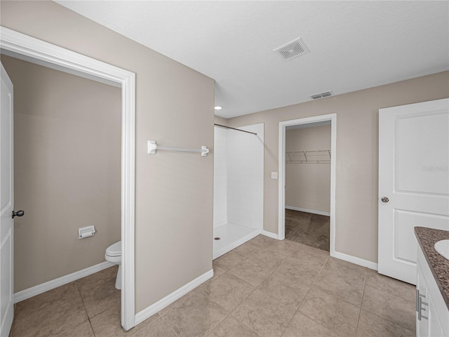 bathroom featuring tile patterned floors, vanity, toilet, and a shower