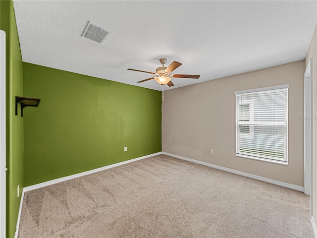 spare room with ceiling fan, light carpet, and a textured ceiling