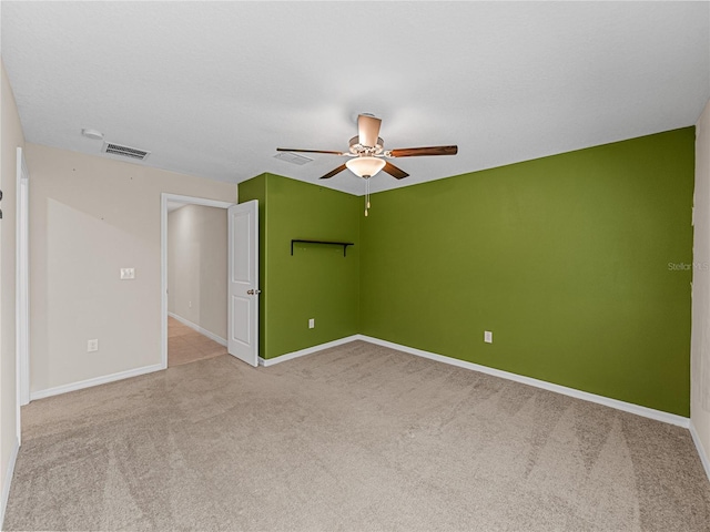 spare room with ceiling fan, light carpet, and a textured ceiling