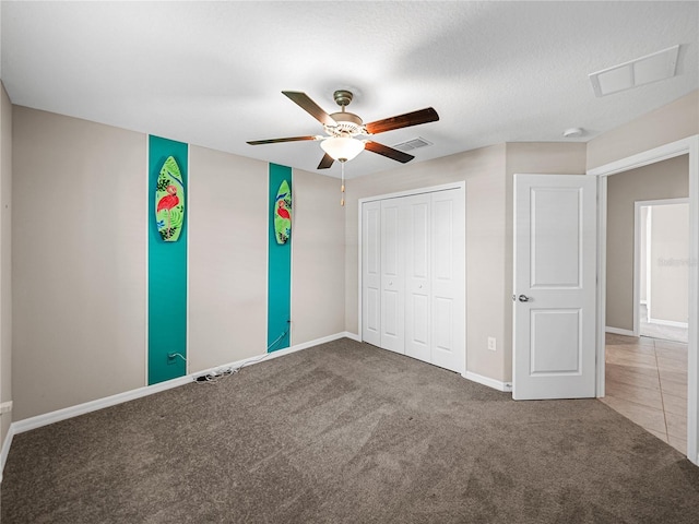 unfurnished bedroom featuring carpet flooring, a textured ceiling, ceiling fan, and a closet