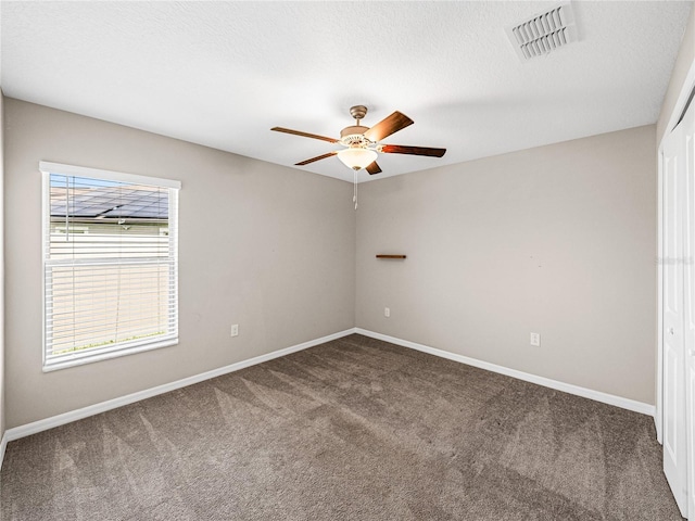 carpeted empty room featuring ceiling fan and a textured ceiling