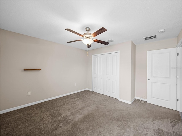 unfurnished bedroom with ceiling fan, a textured ceiling, dark carpet, and a closet