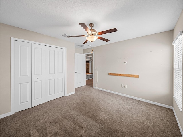 unfurnished bedroom with ceiling fan, carpet flooring, a closet, and a textured ceiling