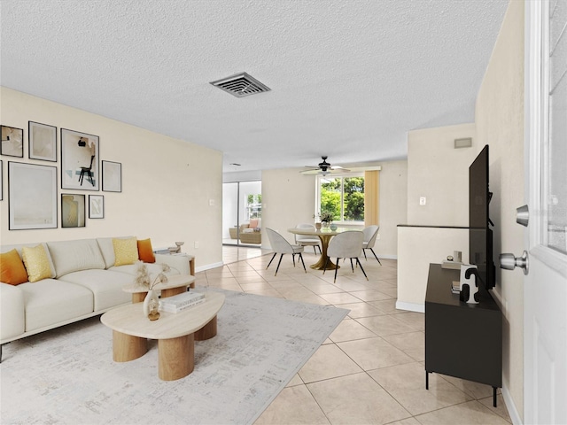 living room with ceiling fan, light tile patterned floors, and a textured ceiling