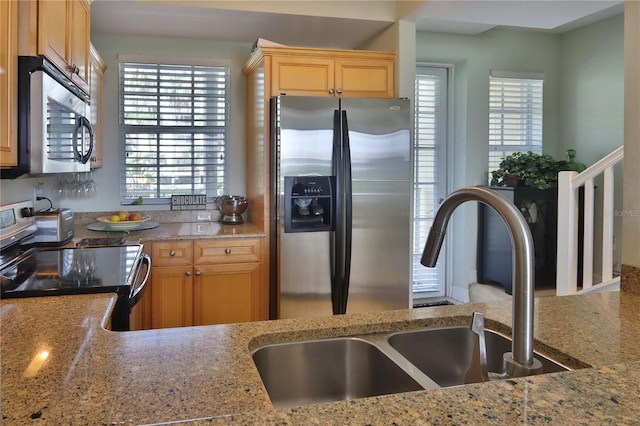 kitchen with stainless steel appliances, light stone countertops, and sink