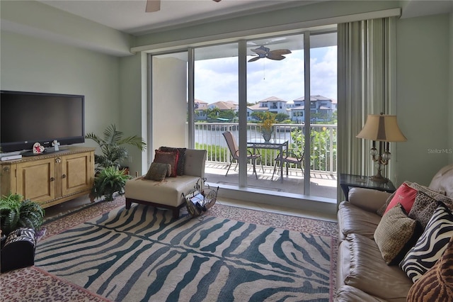 living room featuring a water view, ceiling fan, and plenty of natural light
