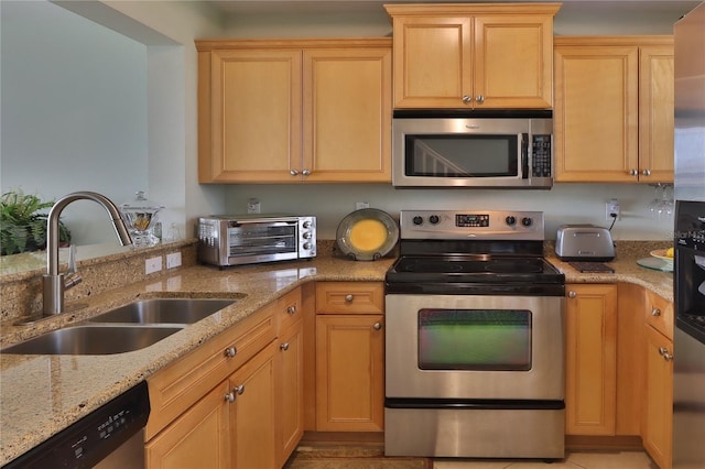 kitchen with light stone counters, stainless steel appliances, sink, and light brown cabinets