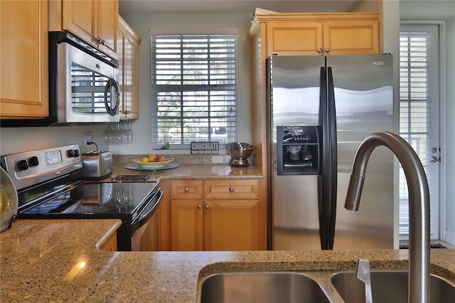 kitchen with light stone counters, sink, and stainless steel appliances