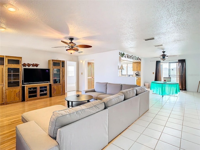 living room with light hardwood / wood-style floors, a textured ceiling, and ceiling fan