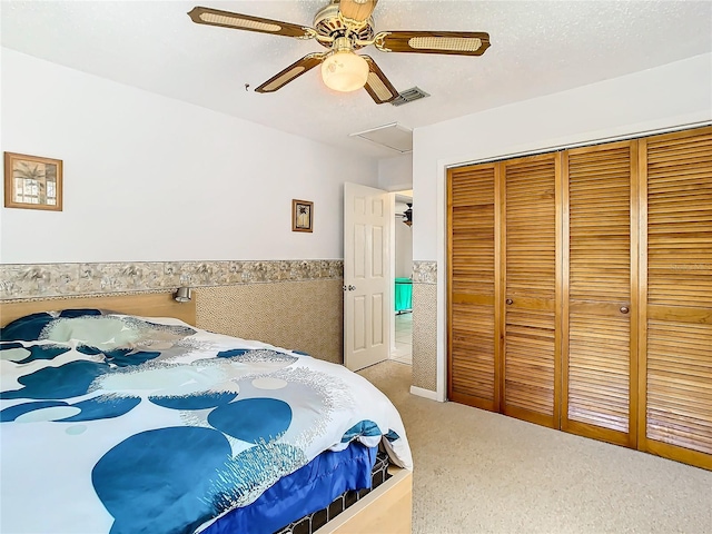 carpeted bedroom featuring a closet, a textured ceiling, and ceiling fan