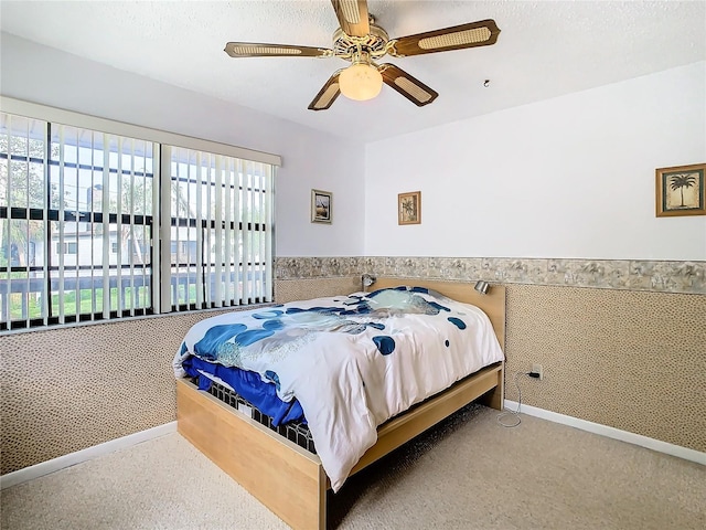 carpeted bedroom featuring a textured ceiling, multiple windows, and ceiling fan