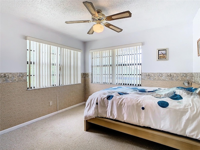 carpeted bedroom featuring a textured ceiling and ceiling fan