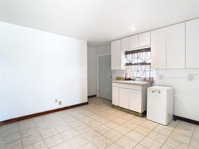 interior space with sink, white cabinets, white refrigerator, and light tile patterned floors