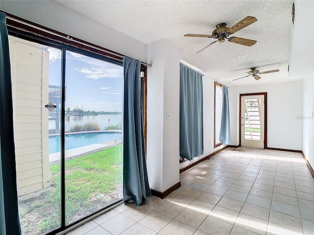 tiled spare room with a textured ceiling and ceiling fan