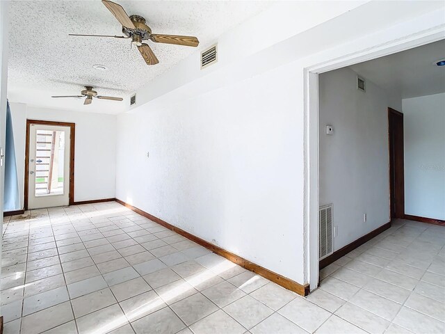 empty room with light tile patterned flooring, a textured ceiling, and ceiling fan