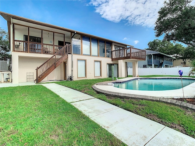 back of house featuring a fenced in pool and a lawn