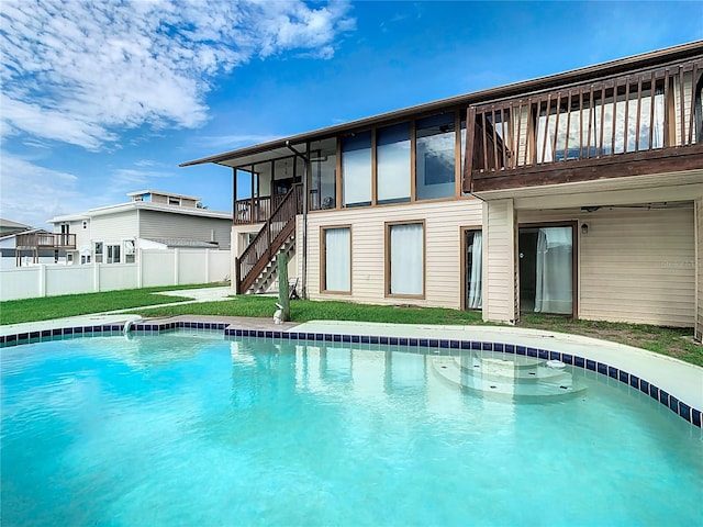 back of house featuring a balcony, a yard, and a fenced in pool