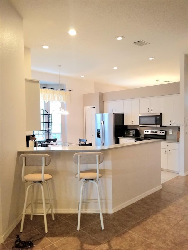 kitchen featuring a breakfast bar, kitchen peninsula, white cabinetry, hanging light fixtures, and stainless steel appliances