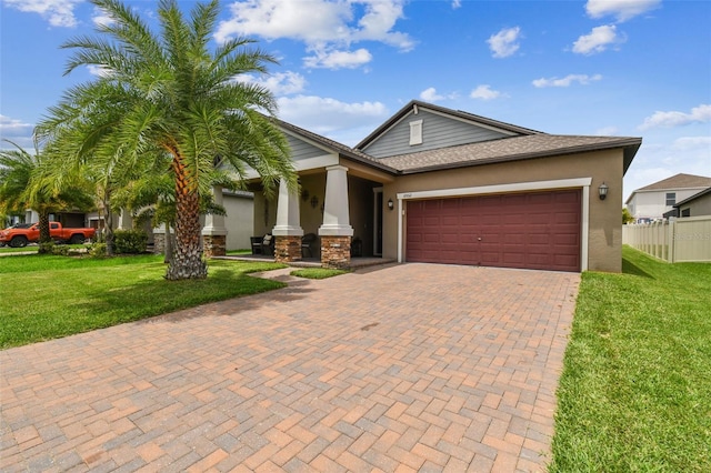 view of front of house featuring a front lawn, fence, decorative driveway, stucco siding, and an attached garage