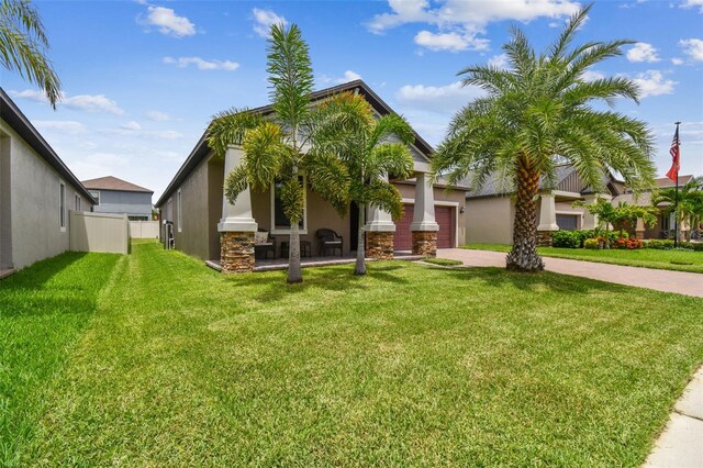 view of front of property with fence, an attached garage, a front lawn, stucco siding, and driveway