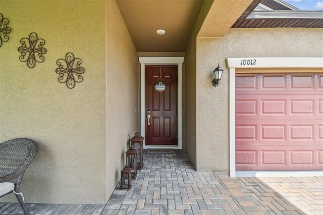 view of exterior entry featuring a garage and stucco siding