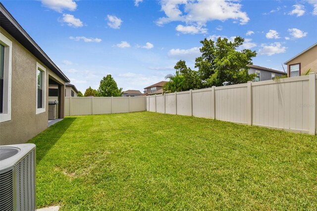view of yard with a fenced backyard and central AC unit