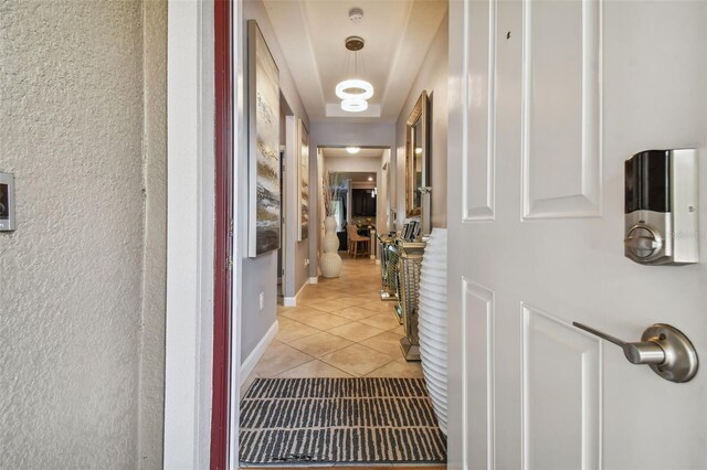 hall with a textured wall and light tile patterned floors