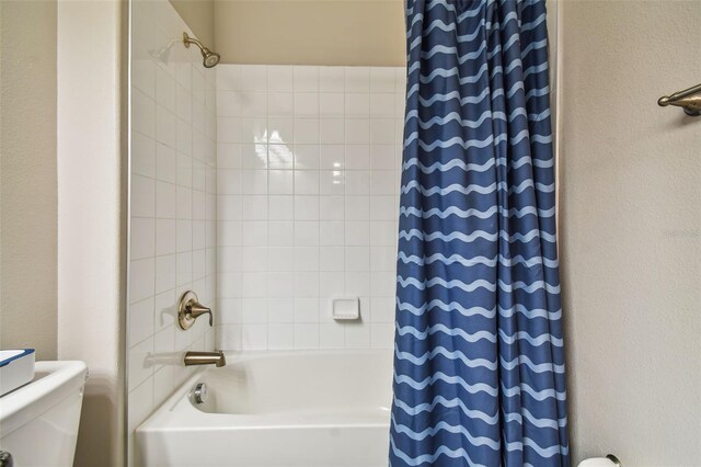 bathroom featuring shower / bath combination with curtain and toilet