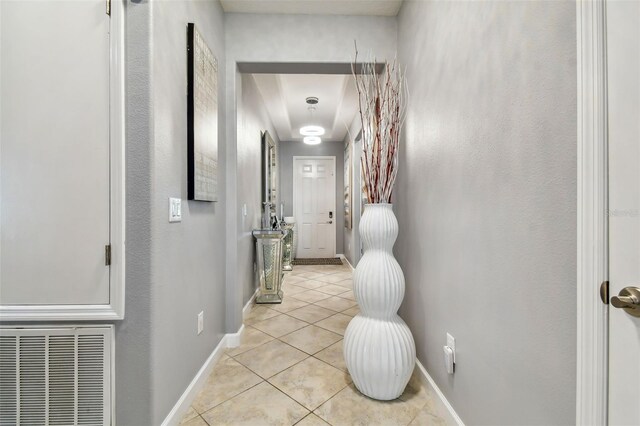 corridor featuring light tile patterned floors, baseboards, and visible vents