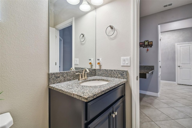 bathroom featuring tile patterned floors, visible vents, a textured wall, and vanity