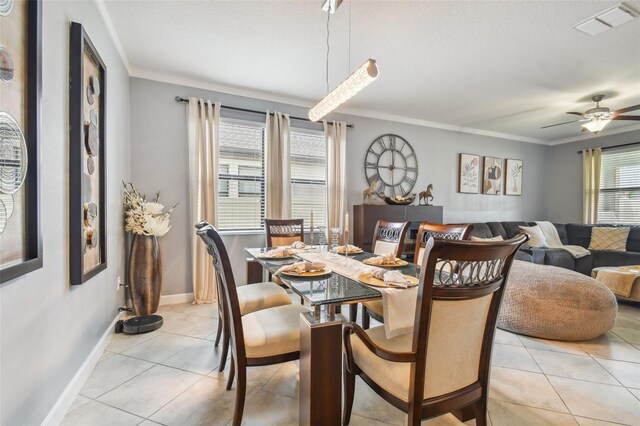 dining space featuring visible vents, crown molding, baseboards, a ceiling fan, and light tile patterned floors