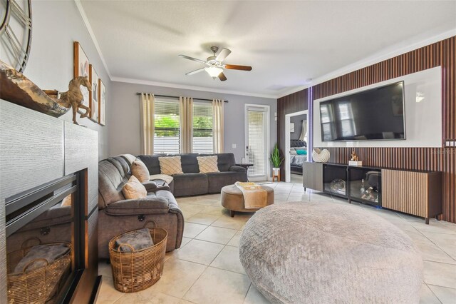 living area featuring crown molding, ceiling fan, light tile patterned floors, and a tile fireplace