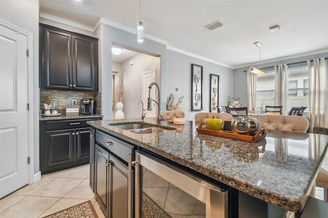 kitchen featuring visible vents, pendant lighting, a kitchen island with sink, beverage cooler, and a sink