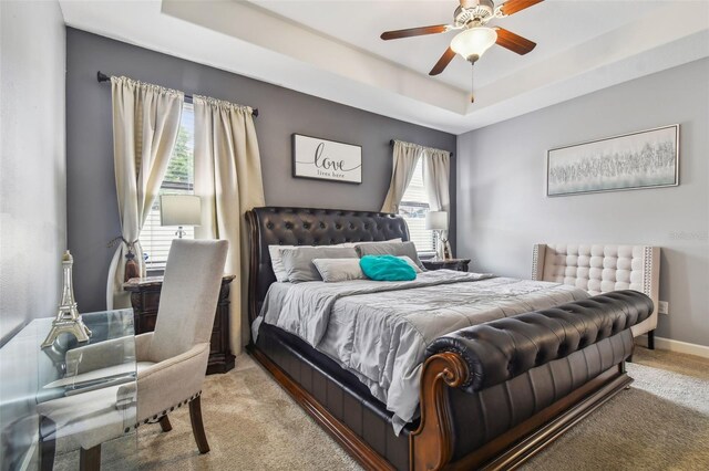 carpeted bedroom with a tray ceiling and ceiling fan
