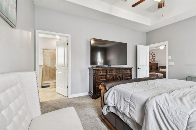 carpeted bedroom with a ceiling fan, baseboards, ensuite bathroom, a tray ceiling, and visible vents
