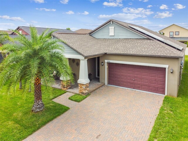 view of front of house with a garage, a front lawn, decorative driveway, roof with shingles, and stucco siding