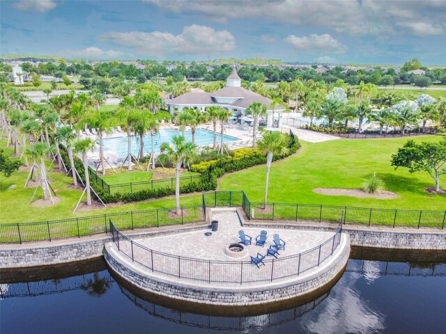 view of property's community with a lawn, a water view, and fence
