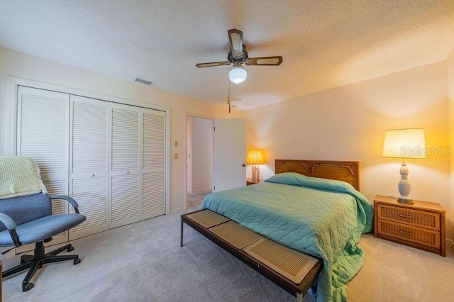 carpeted bedroom with a textured ceiling, a closet, and ceiling fan