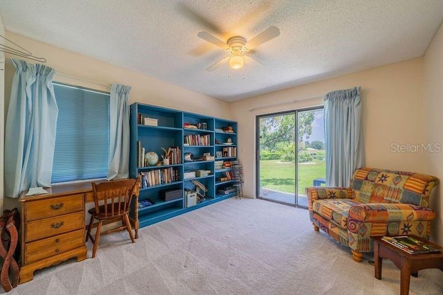 sitting room featuring ceiling fan, light carpet, and a textured ceiling