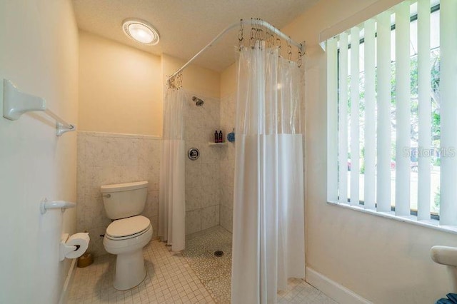 bathroom with toilet, a shower with shower curtain, and tile walls